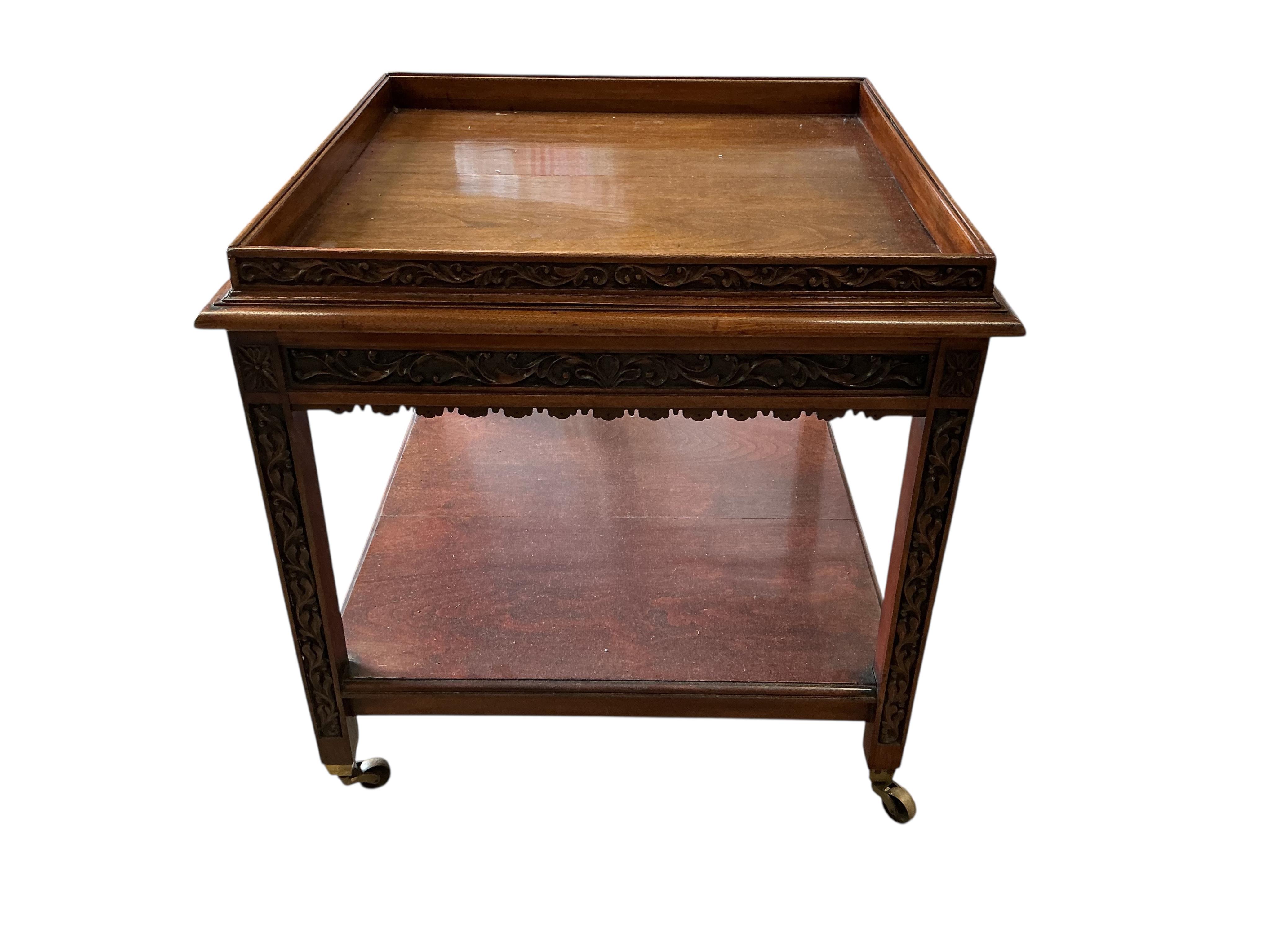 An early 20th century carved walnut square two tier occasional table, with brass caps and casters, 76cm, height 76cm